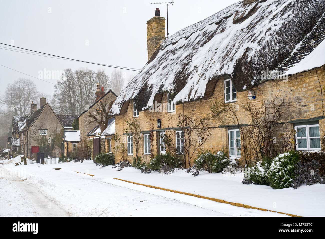 Reetgedeckte Ferienhaus aus Stein im Winter Schnee. Minster Lovell, Oxfordshire, England Stockfoto