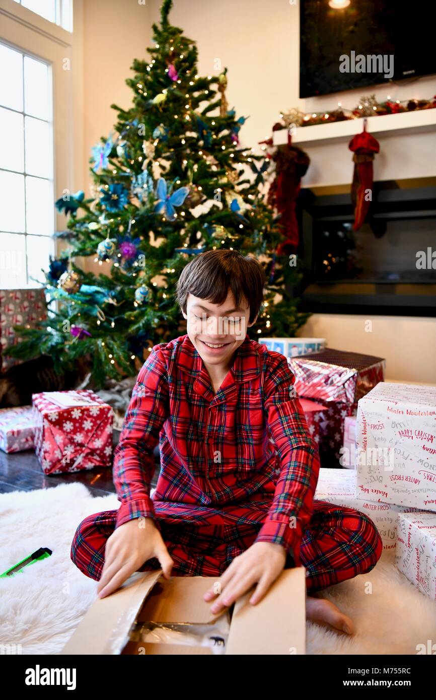 Jugendliche 10-14 auf Weihnachten Morgen neben dem Weihnachtsbaum mit Geschenken im Alter von Stockfoto