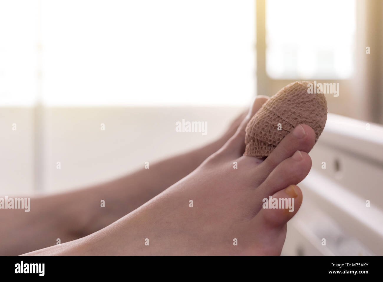 Nahaufnahme der Verband index Zehe der weiblichen Patienten schlafen im Bett des Patienten nach einem Unfall mit Sunbeam Stockfoto