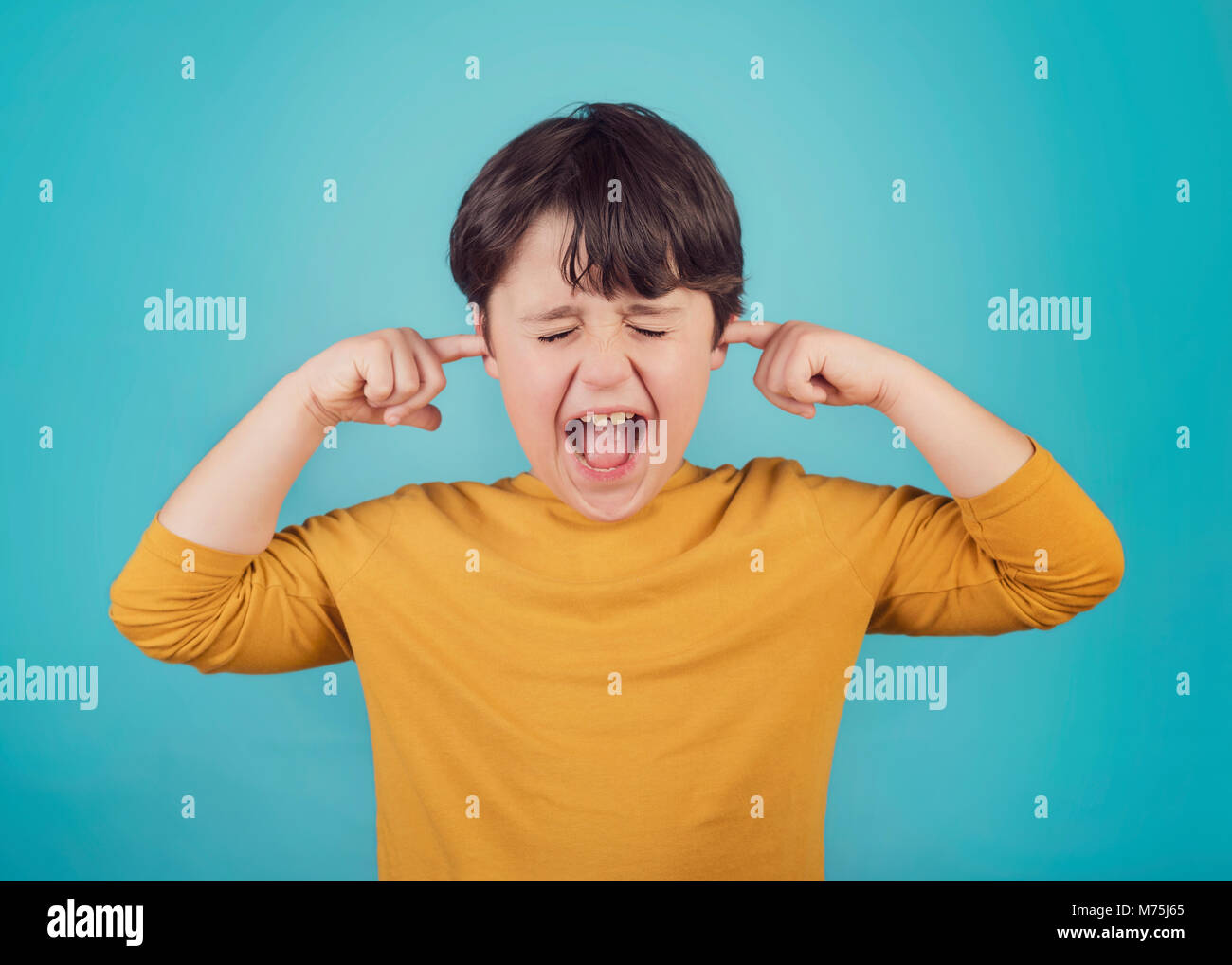 Porträt von einem schreienden kleinen Jungen, die Ohren mit den Händen Stockfoto