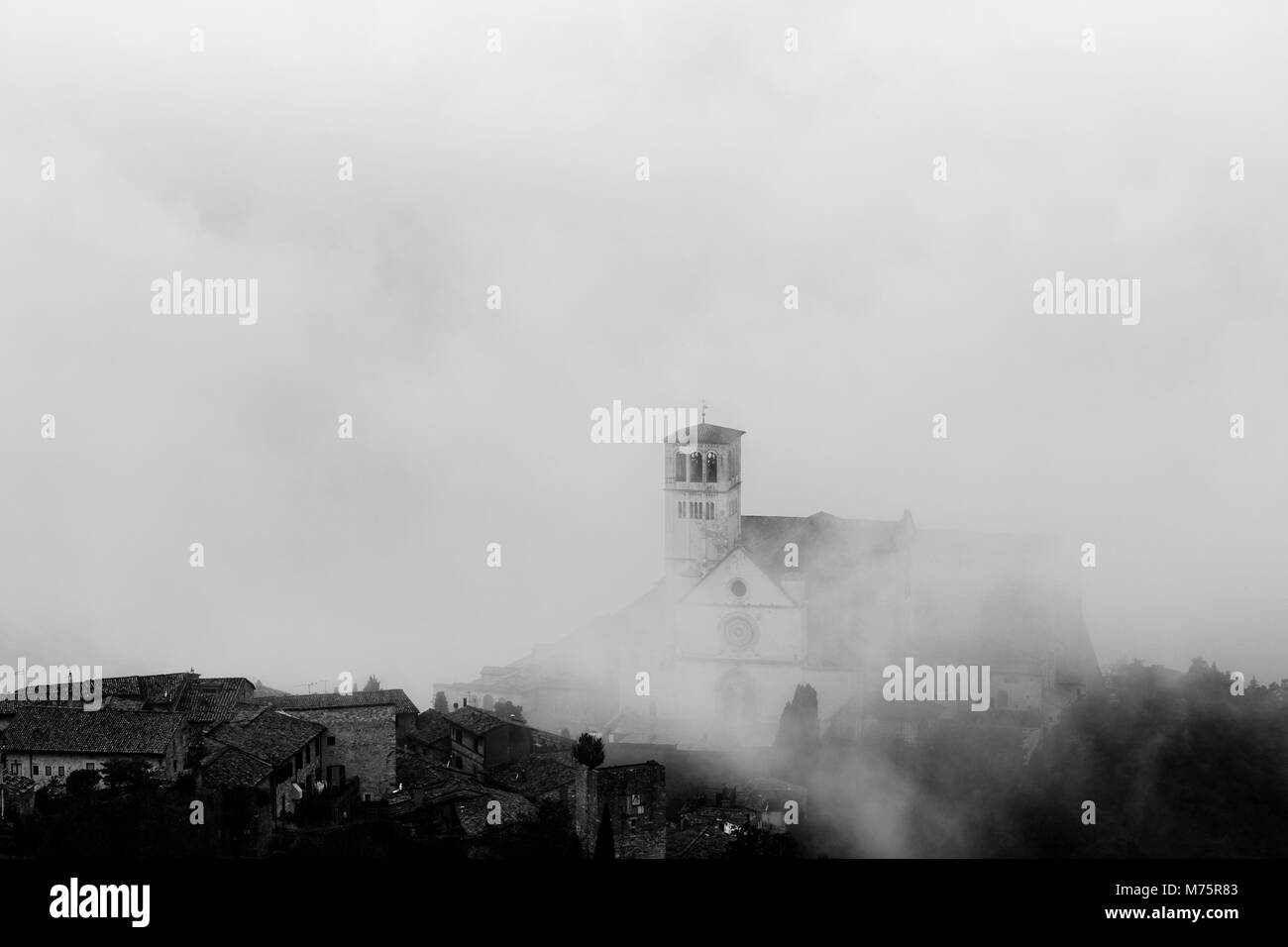 Blick auf die St. Francis päpstliche Kirche in Assisi (Umbrien, Italien) in der Mitte der Aufhebung Morgennebel Stockfoto