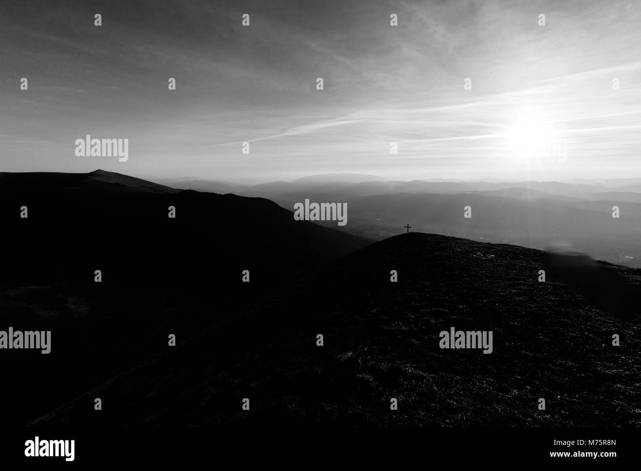 Kreuz auf dem Gipfel des Mt. Serrasanta (Umbrien, Italien), mit Sun niedrig am Horizont Stockfoto