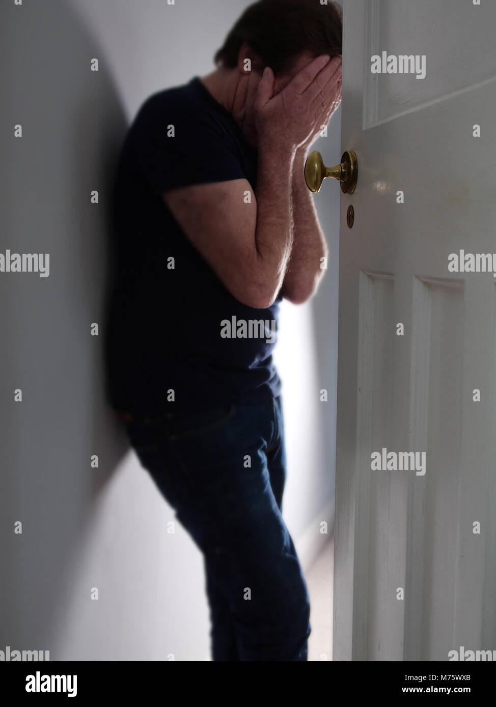Mann mit Kopf in den Händen, die in der Tür gedrückt Stockfoto