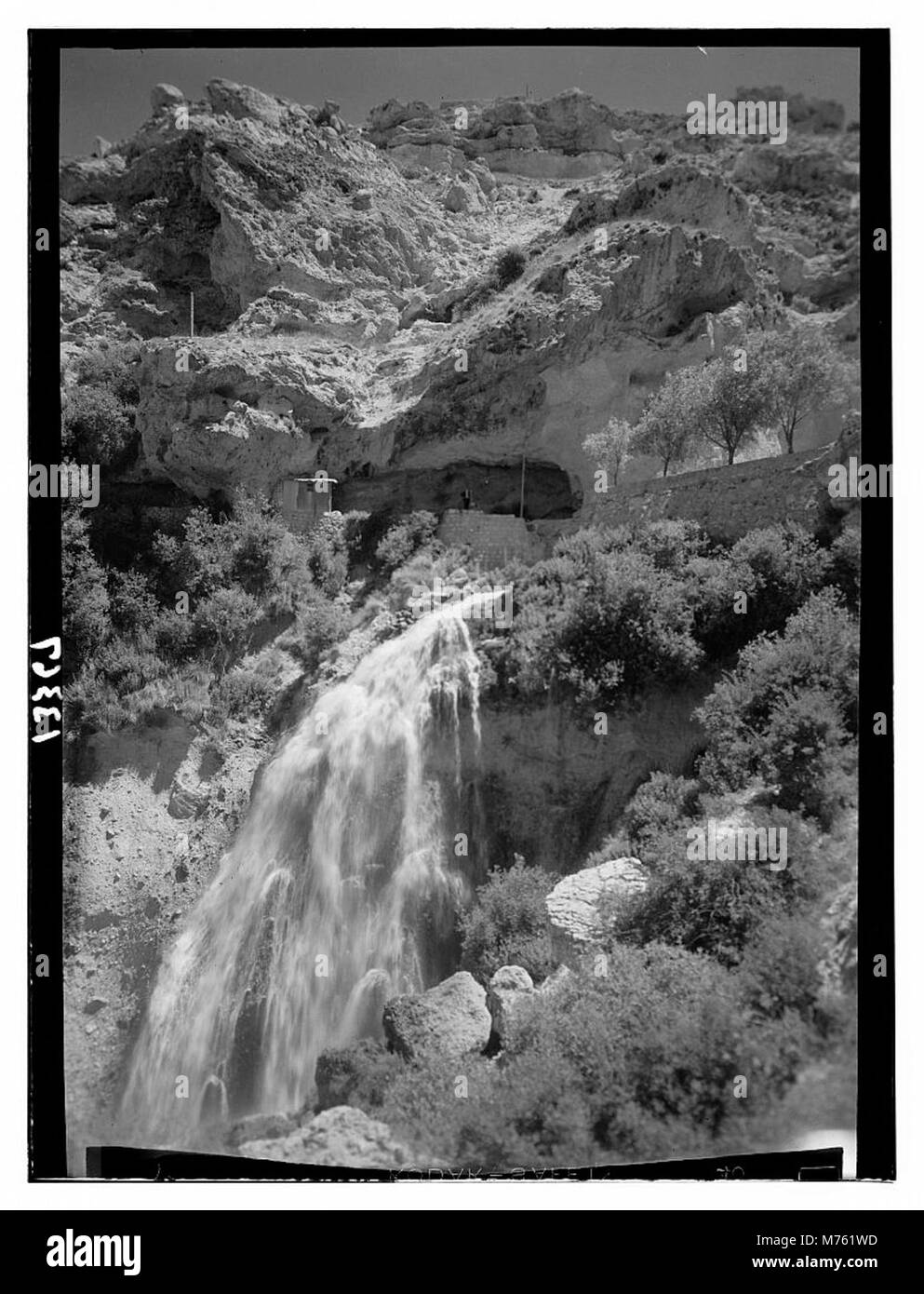 Das Bild zeigt Kadeesha Falls mit Blick auf den Eingang zu einer Höhle, eingerahmt von der Landschaft und Skyline darüber. Die natürliche Schönheit der Wasserfälle und der Umgebung wird auf diesem Foto festgehalten. Stockfoto