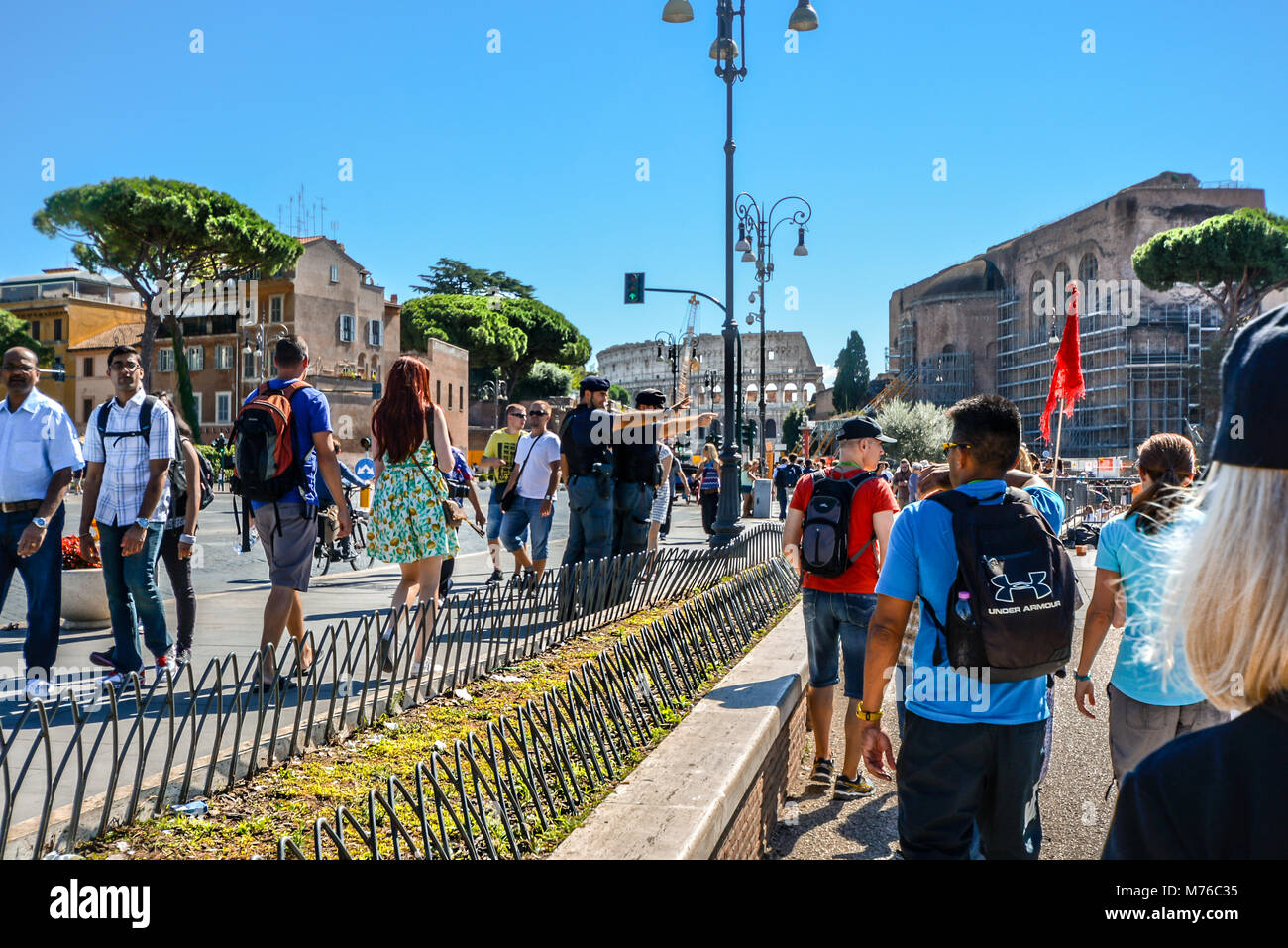 Italienische Polizisten Punkt über die Straße vor Touristen auf der Via dei Fori Imperiali in Rom Italien mit dem römischen Kolosseum und dem Forum hinter Stockfoto