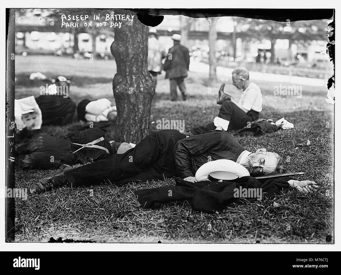 Eine Person wird an einem heißen Tag im Battery Park im Schlaf gefangen genommen, was die friedliche und dennoch urbane Atmosphäre des Parks unterstreicht. Das Bild reflektiert einen Moment der Erholung im Stadtleben. Stockfoto