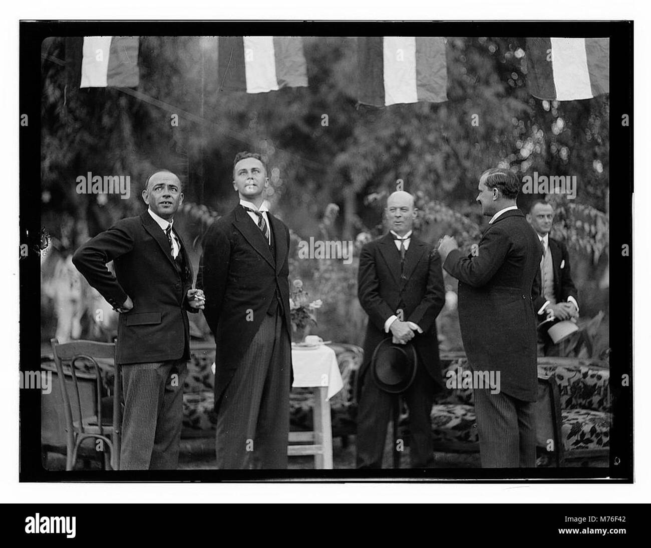 Ein historisches Foto, das am 6. Oktober 1932 in Bagdad aufgenommen wurde und vier Männer zeigt, von denen drei in Schwänze gekleidet sind, wahrscheinlich bei einer formellen Veranstaltung oder Versammlung. Stockfoto