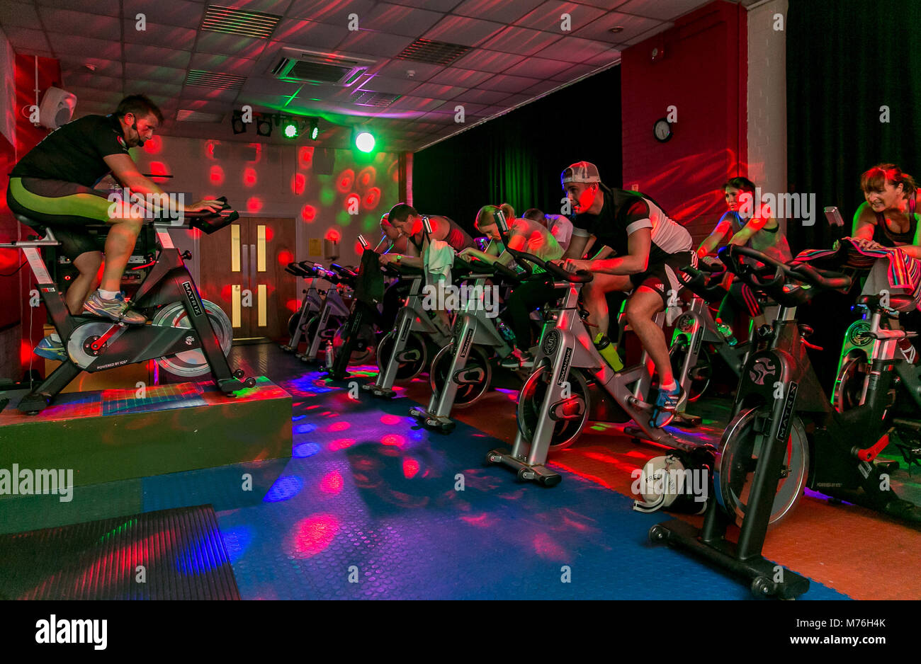 Gemischte spinning Klasse mit blinkenden Disco lights im Health Club. Stockfoto