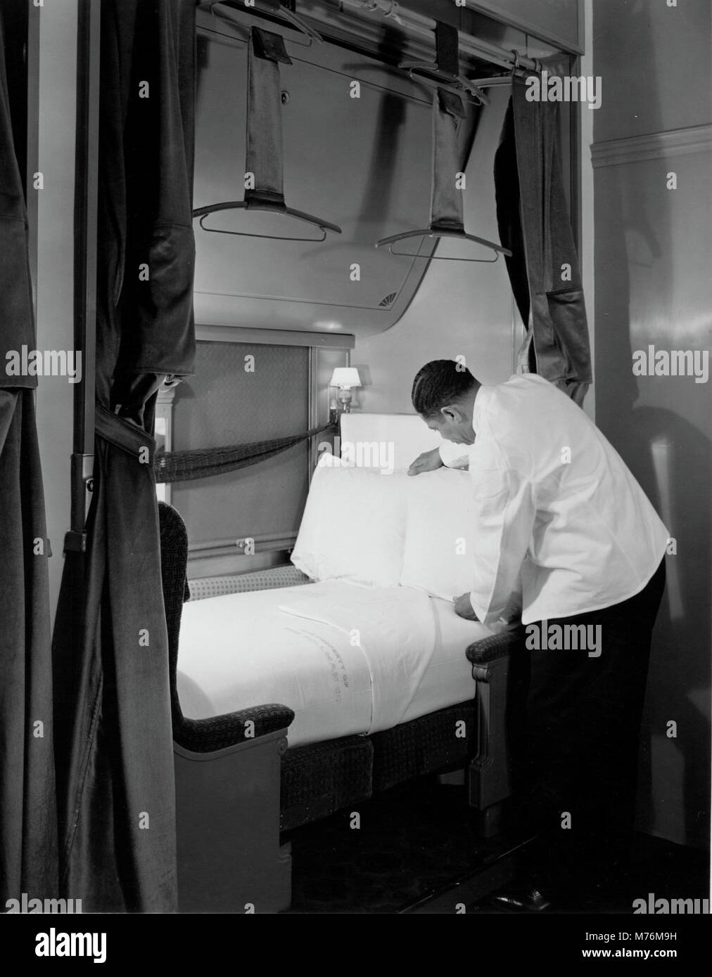 Ein Foto, das einen Pullman-Porter zeigt, der ein Bett in einem 1940er-Wagen vorbereitet. Dieses Bild fängt einen Moment in der Geschichte der amerikanischen Zugreisen ein und unterstreicht den Service und die Gastfreundschaft der Pullman-Träger. Stockfoto