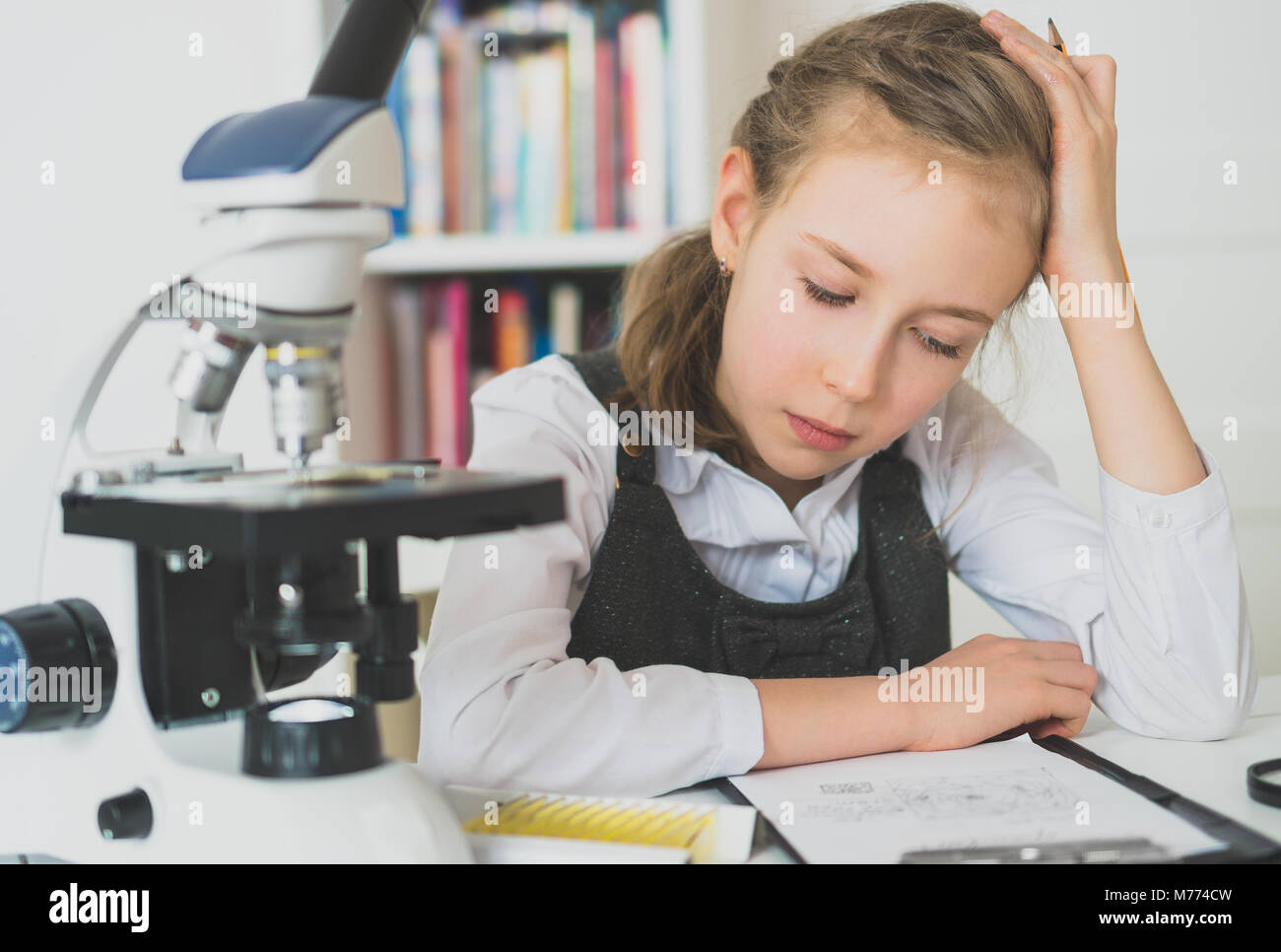 Kleines Mädchen in Wissenschaft Kategorie mit Mikroskop auf dem Tisch. Stockfoto