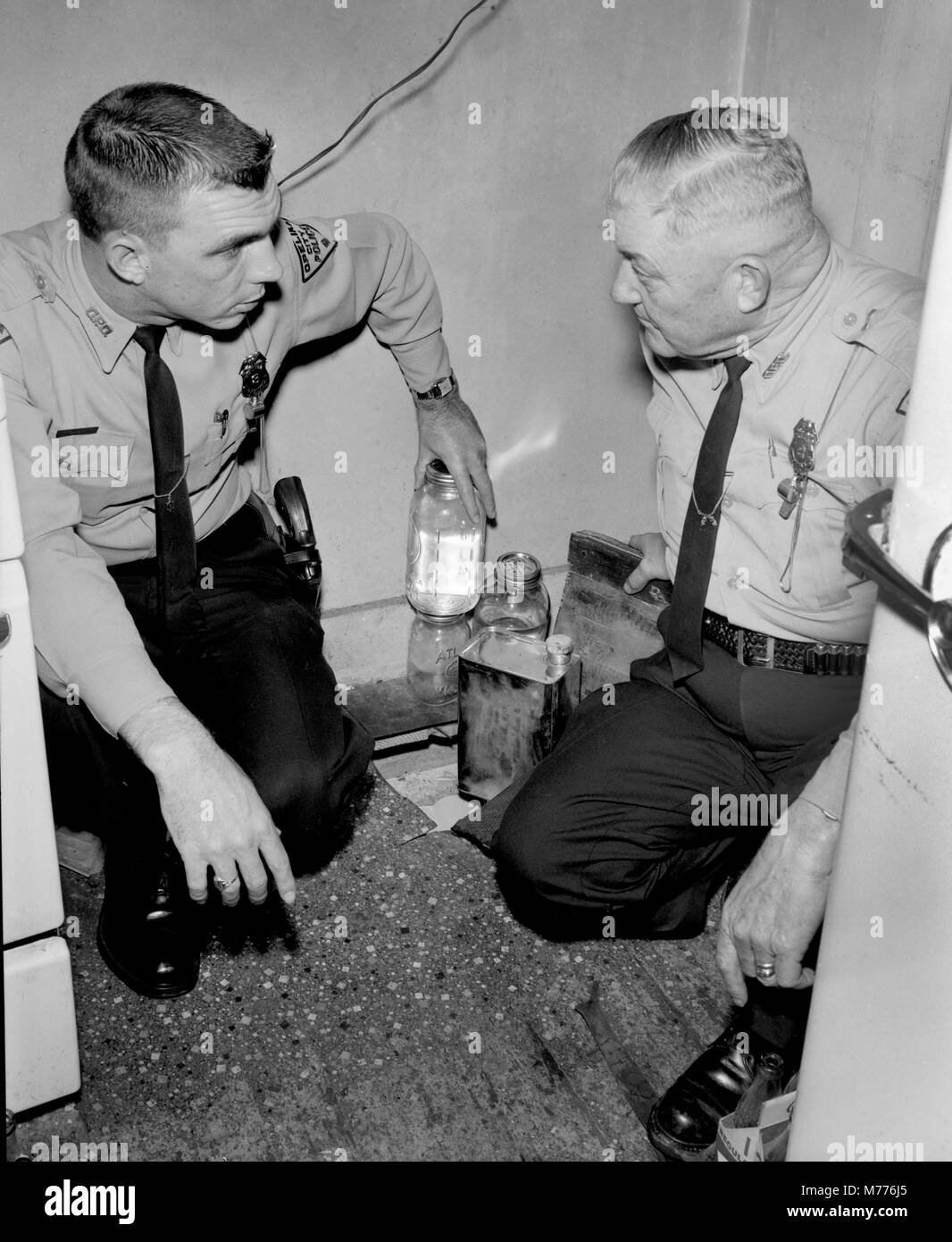 Die Polizei im US-Bundesstaat Georgia untersuchen illegale Moonshine unter einer Klappe in einem ländlichen Heimat versteckt, Ca. 1962. Stockfoto