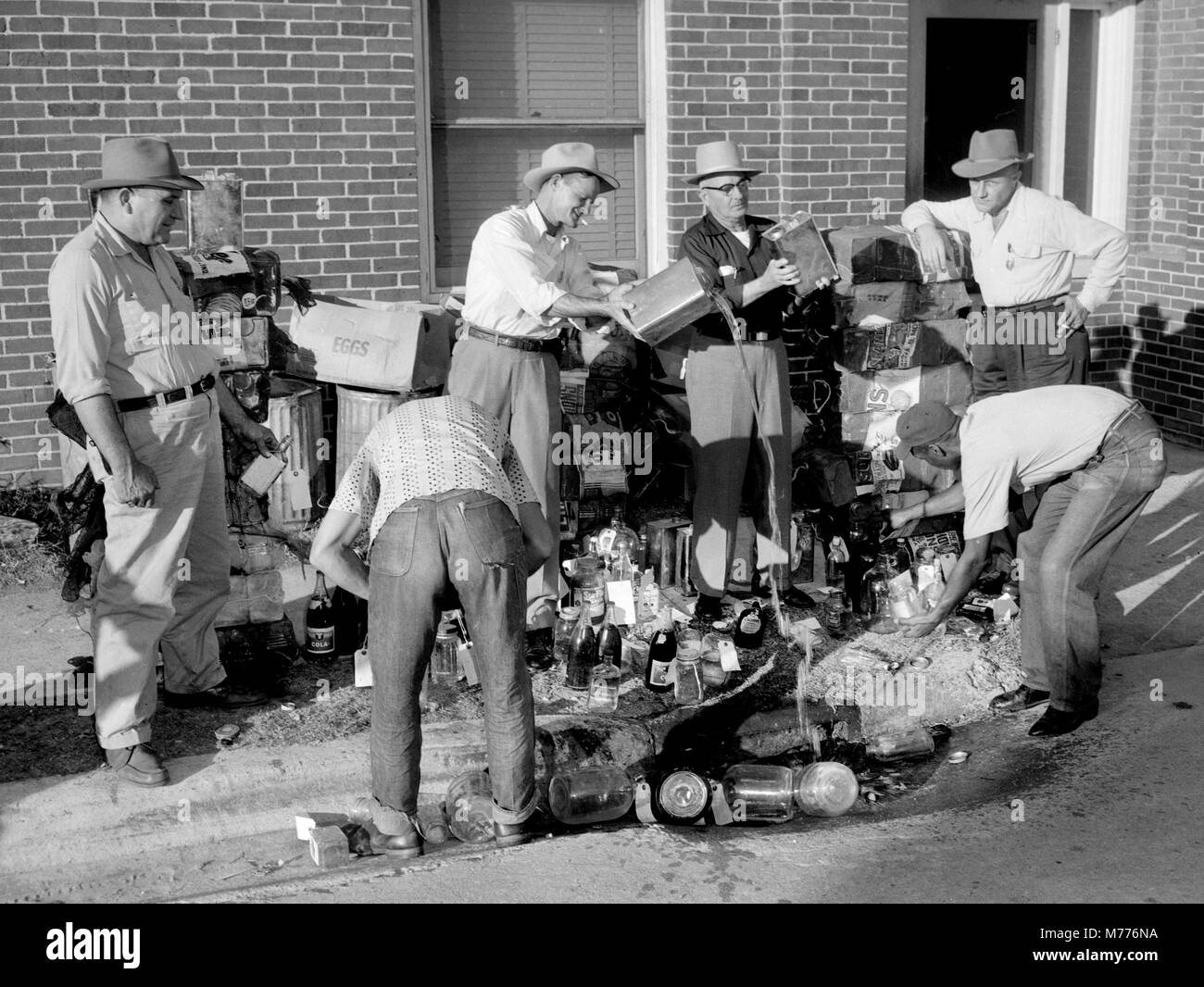 Stadt Arbeitnehmer dump Illegale moonshine Schnaps nach einem Sturm nach einem Überfall auf die noch in Georgia, Ca. 1955. Stockfoto Stadt Arbeitnehmer dump Illegale moonshine Schnaps nach einem Sturm nach einem Überfall auf die noch in Georgia, Ca. 1955. Stockfoto