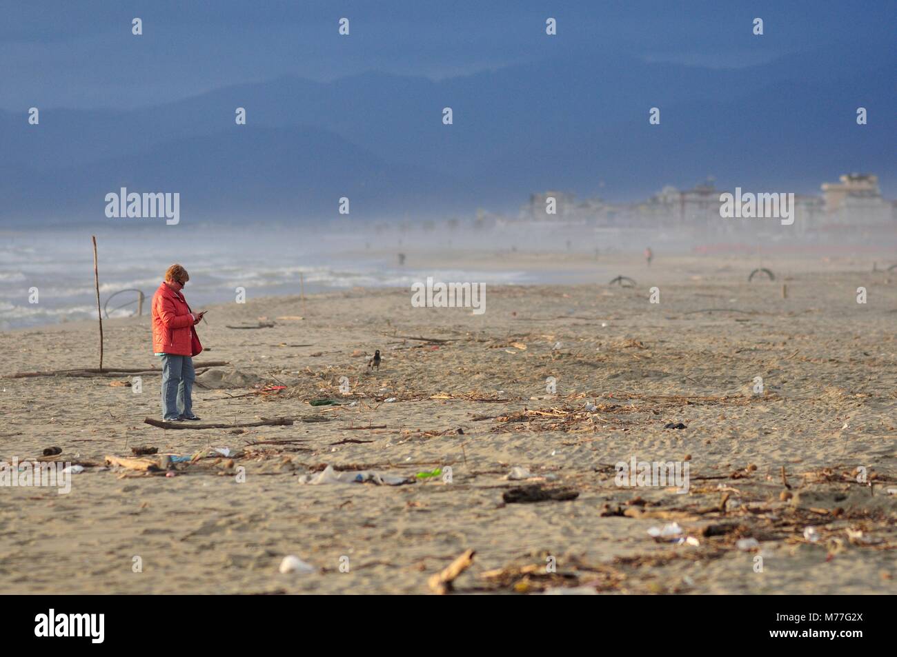 Reife Frau mit Telefon in einer verschmutzten Strand Stockfoto