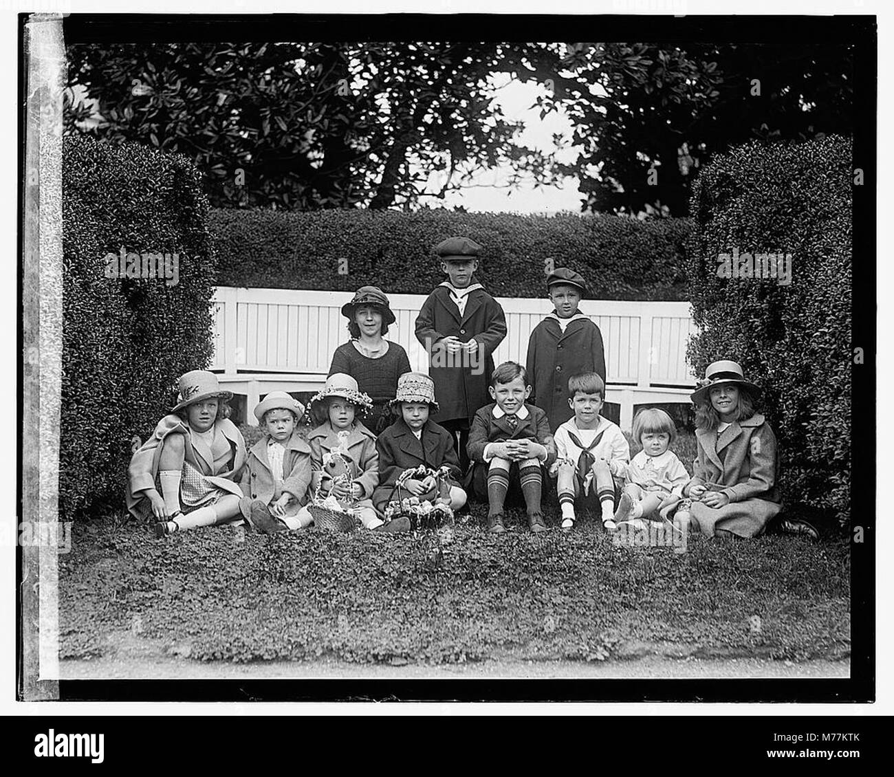 Eine Vintage-Fotografie mit Kindern in einer Schrankposition, wahrscheinlich um Ostern 1922 aufgenommen, die einen Moment in der Geschichte der Kindheit festnimmt, während die Kinder in Osterkleidung gekleidet und in einem Studio-Setting inszeniert sind. Stockfoto