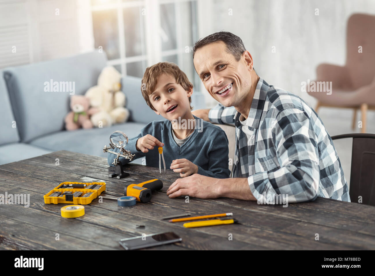 Lächelnde junge Holding Kompasse und sitzt mit seinem Daddy Stockfoto