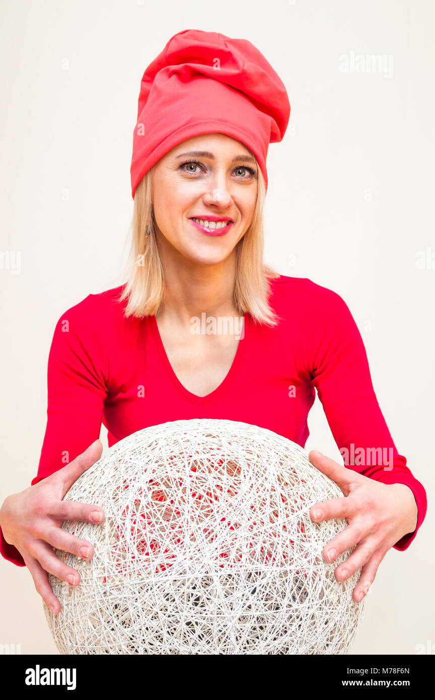 Red Hat und Kleid lächelnde blonde Frau umarmt riesigen weissen Korbmöbeln ball Portrait auf weißem Hintergrund. Stockfoto