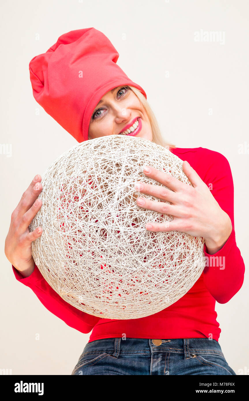 Red Hat und Kleid lächelnde blonde Frau umarmt riesigen weissen Korbmöbeln ball Portrait auf weißem Hintergrund. Stockfoto