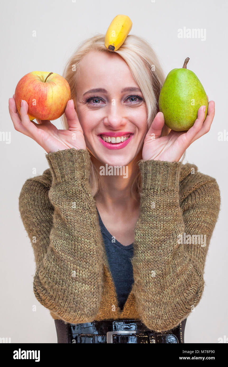 Menschen mit Obst und Gemse. Gesunde Lebensweise. Junge lchelnde Frau,  Apfel Birne und Banane auf ihrem Kopf Stockfotografie - Alamy