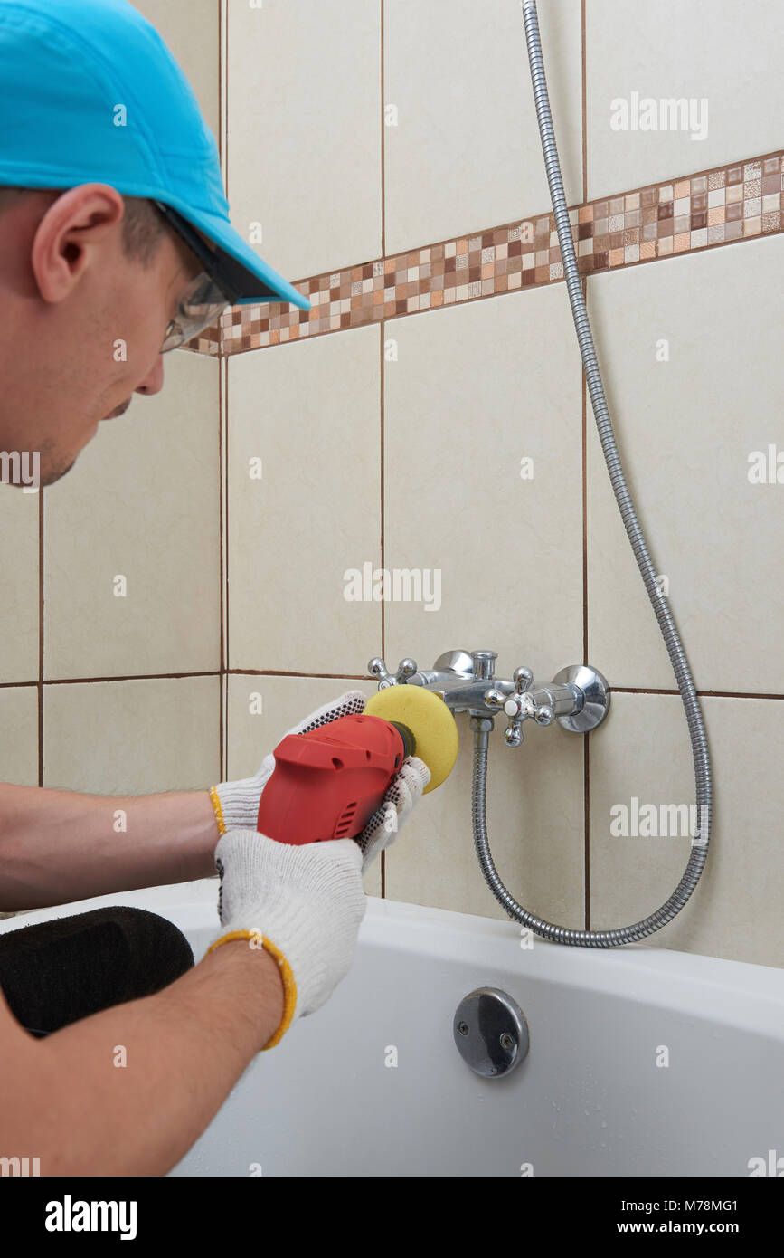 Arbeitnehmer polieren Wasserhahn im Bad. Professionelle Reinigung Stockfoto