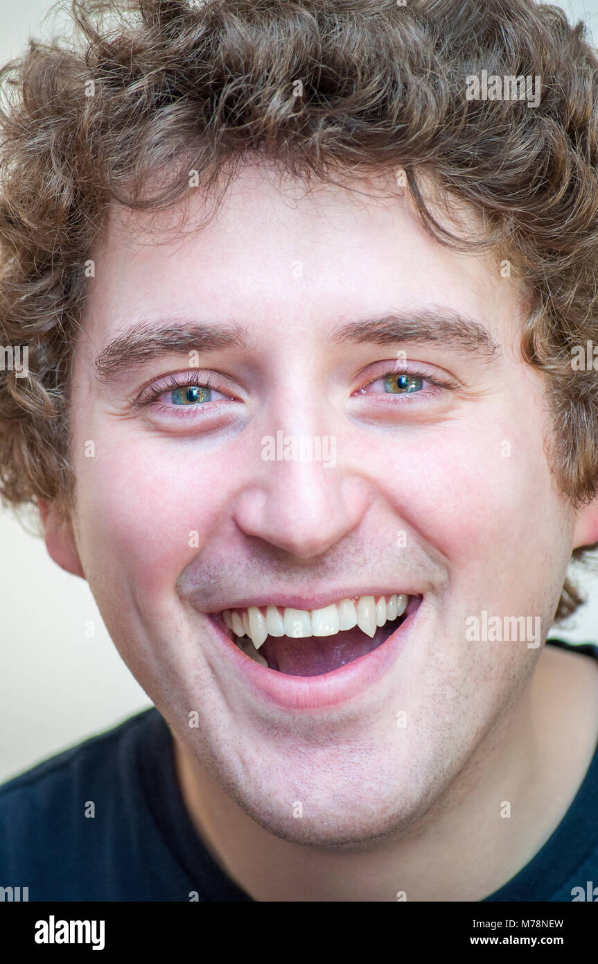 Porträt der jungen positive lächelnden Jungen curly Grünäugige Vampir Mann auf weißem Hintergrund. Stockfoto