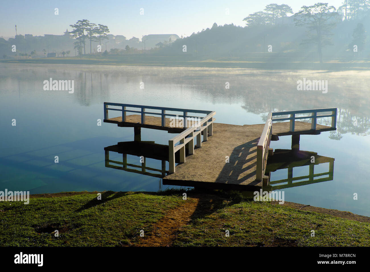 Ziel für Vietnam Reisen in der Stadt Da Lat, Nebel von der Oberfläche Wasser des Sees verdunsten, Silhouette der kleinen Brücke reflektieren auf Teich, bei Sonnenaufgang schön Stockfoto