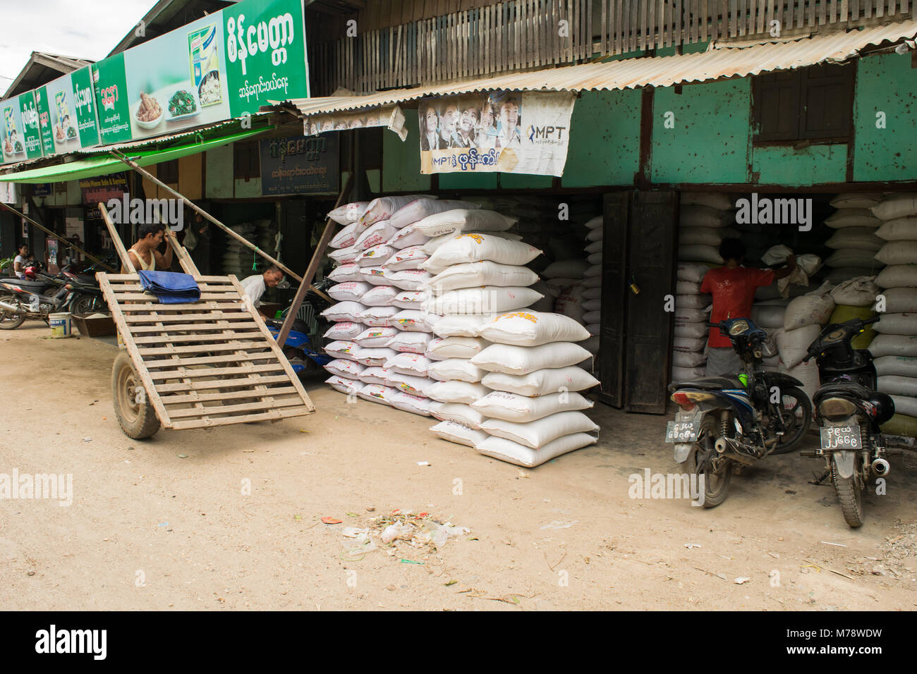 Ein Anbieter in Nyaung U Markt verkaufen Säcke Reis oder Mehl. Die burmesische Mann mit behelfsmäßigen Holz Karre mit Auto Reifen und Räder. Bagan, Myanmar, Birma Stockfoto