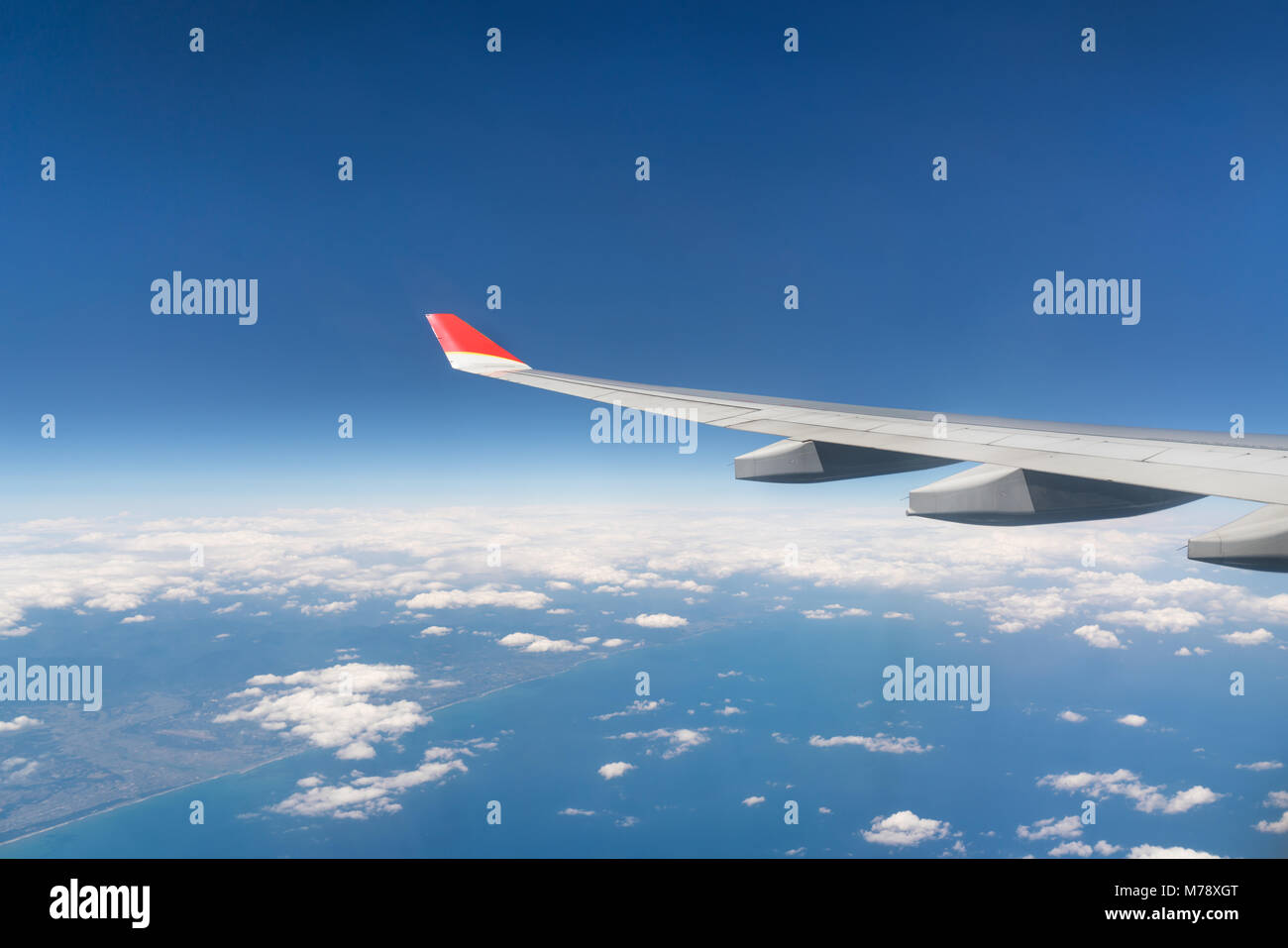 Blick aus dem Flugzeugfenster mit blauem Himmel und weißen Wolken Stockfoto