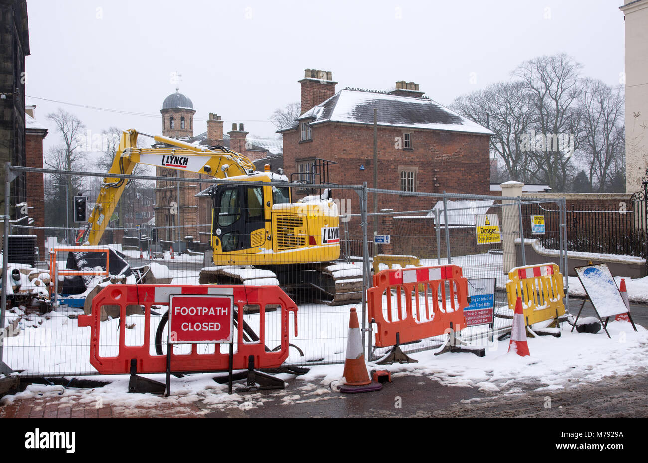 Wanderweg geschlossen Zeichen Barrieren Straße an der Kreuzung der Engen und Beacon Street auf verschneiten Tag arbeitet in Lichfield Gelb Lynch Mechanische Bagger auf der Baustelle Stockfoto