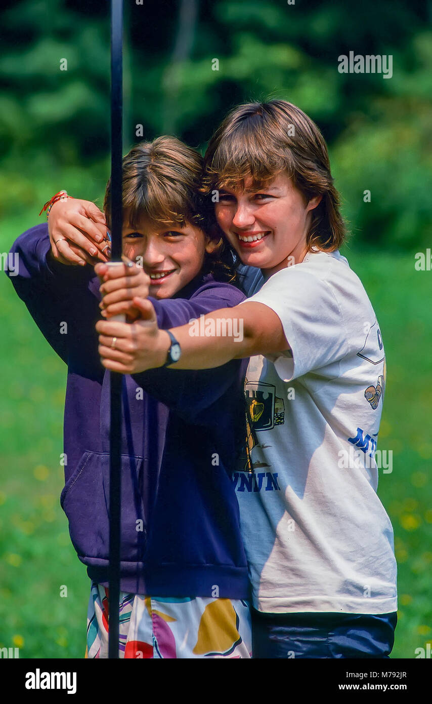 Eine elementare Alter Mädchen erhält Bogenschießen aus ihrem Ratgeber an ein Sommer Camp in Vermont, USA, Nordamerika. Stockfoto