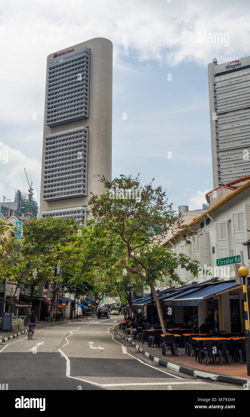 Von Bäumen gesäumten Circular Road, und die Reihe der traditionellen Shophouses kontrastieren mit den Wolkenkratzern der Innenstadt von Singapur. Stockfoto