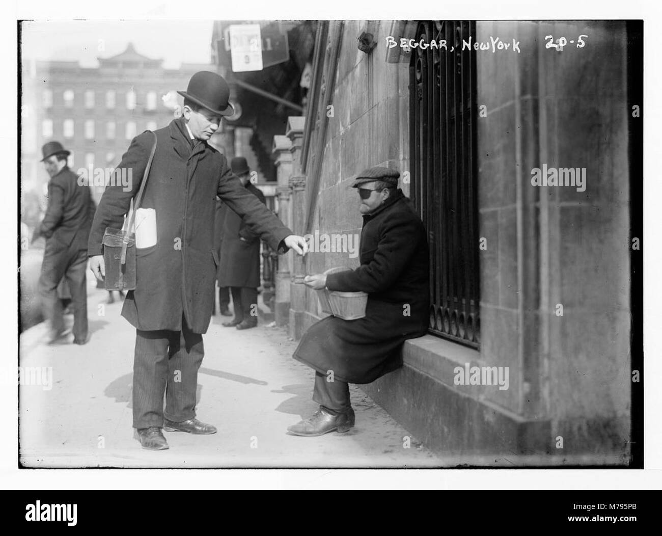 Dieses Foto zeigt einen Bettler, der Geld auf einer New Yorker Straße erhält und die sozialen und wirtschaftlichen Bedingungen des frühen 20. Jahrhunderts widerspiegelt. Das Bild bietet einen Einblick in die Realität von Armut und Wohltätigkeit in dieser Zeit. Stockfoto