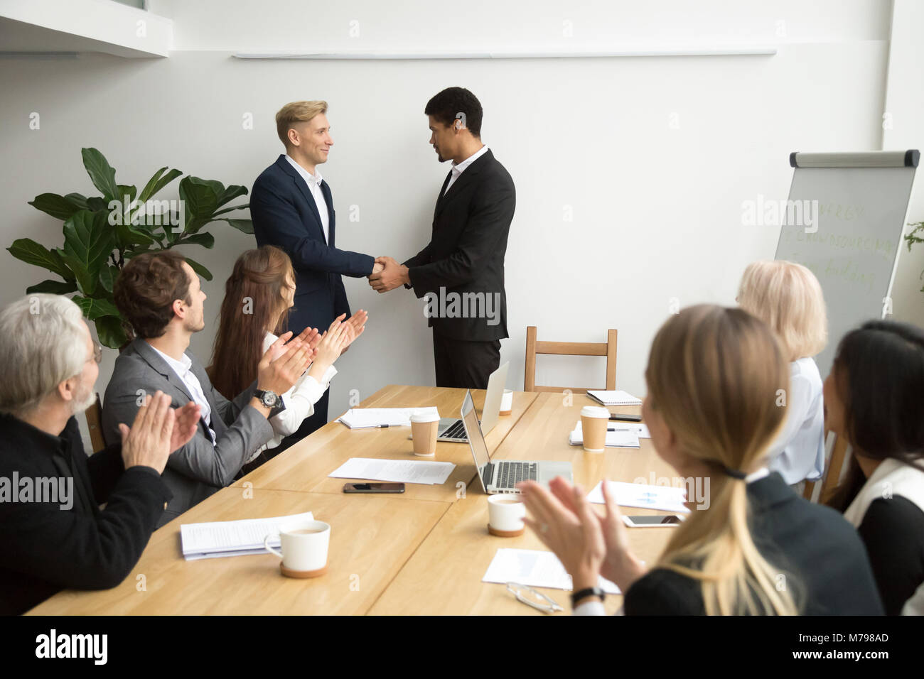 Team applaudieren, schwarze und weiße Mitarbeiter schütteln ceo Stockfoto