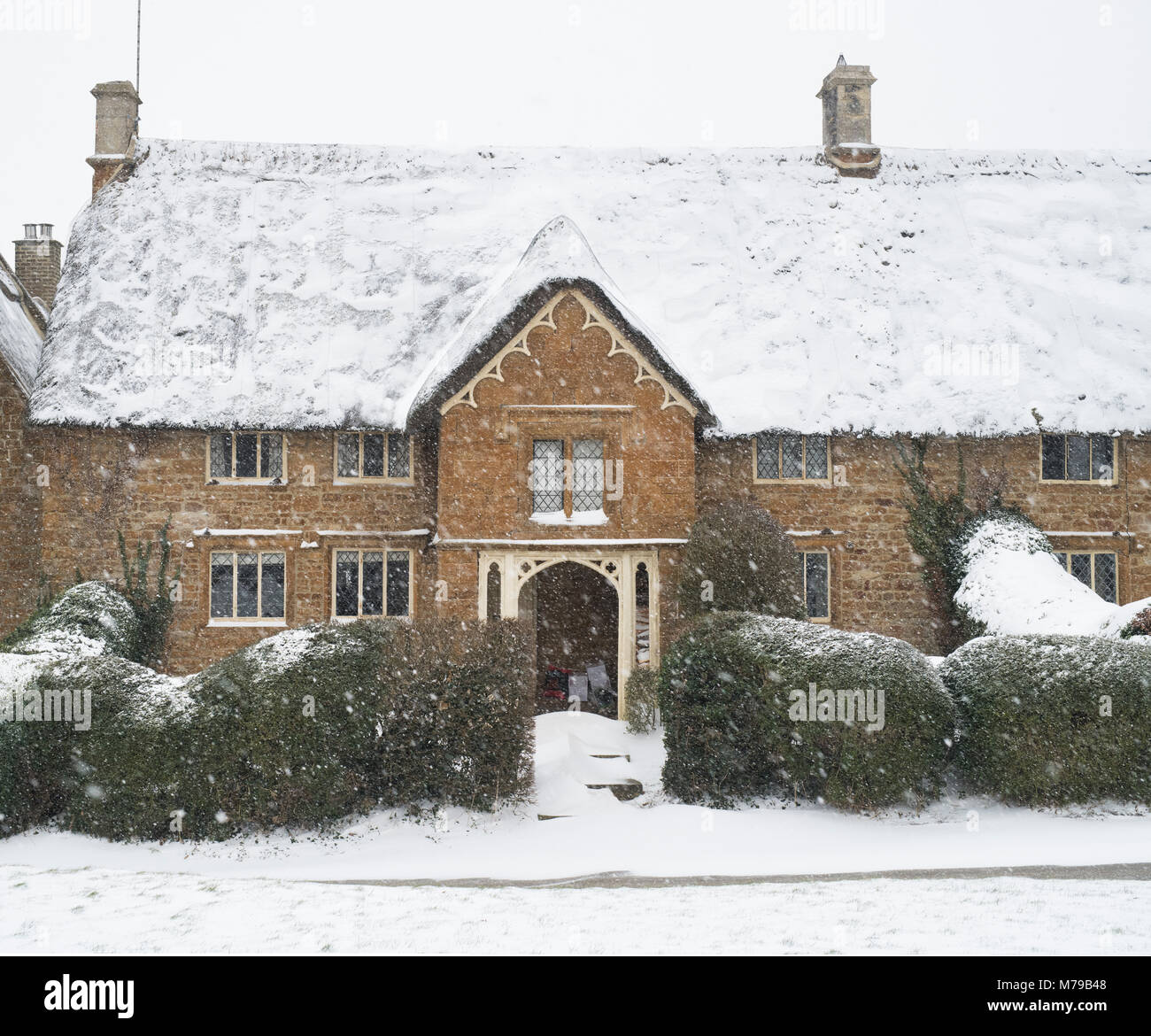 Reetgedeckte Ferienhaus aus Stein im Winter Schnee. Große Tew, Cotswolds, Oxfordshire, England Stockfoto