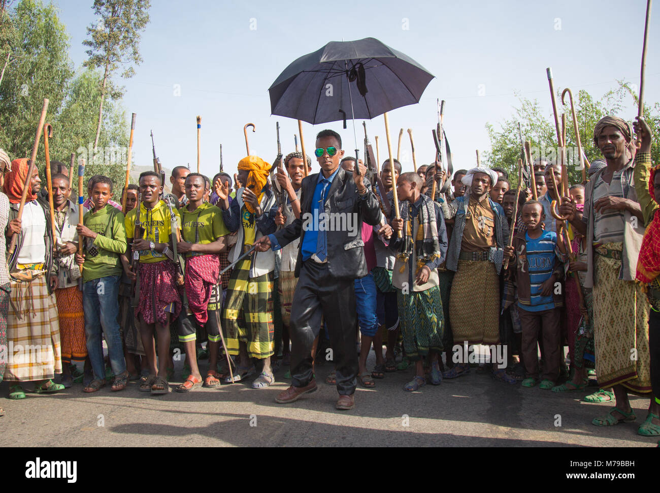 Eine oromo Bräutigam mit Sonnenbrille und ein Regenschirm, Tanzen und gerne feiert seine Hochzeit mit seiner Verwandten Männer und Jungen, Oromo region, Sambate, Stockfoto