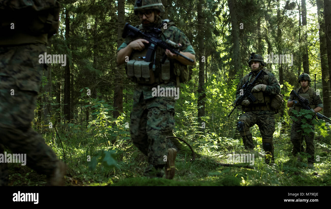 Gruppe von fünf voll ausgestatteten Soldaten auf eine Aufklärung der Bundeswehr. Sie bewegen sich in Formation durch dichten Wald. Stockfoto