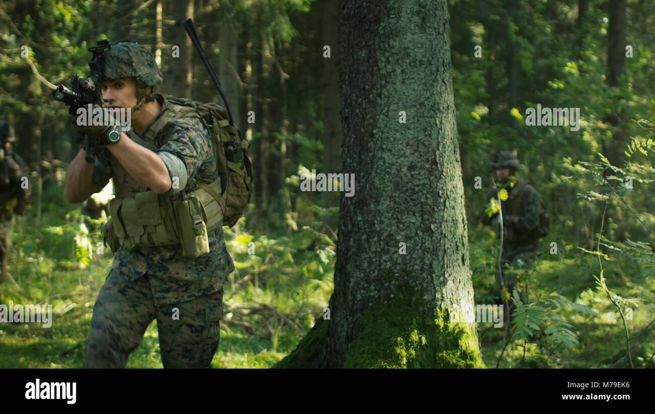 Voll Soldat in der Tarnung auf eine Aufklärung der Militärischen Mission ausgestattet, auf den Feind Zielen. Er bewegt sich in der Ausbildung durch dichten Wald. Stockfoto