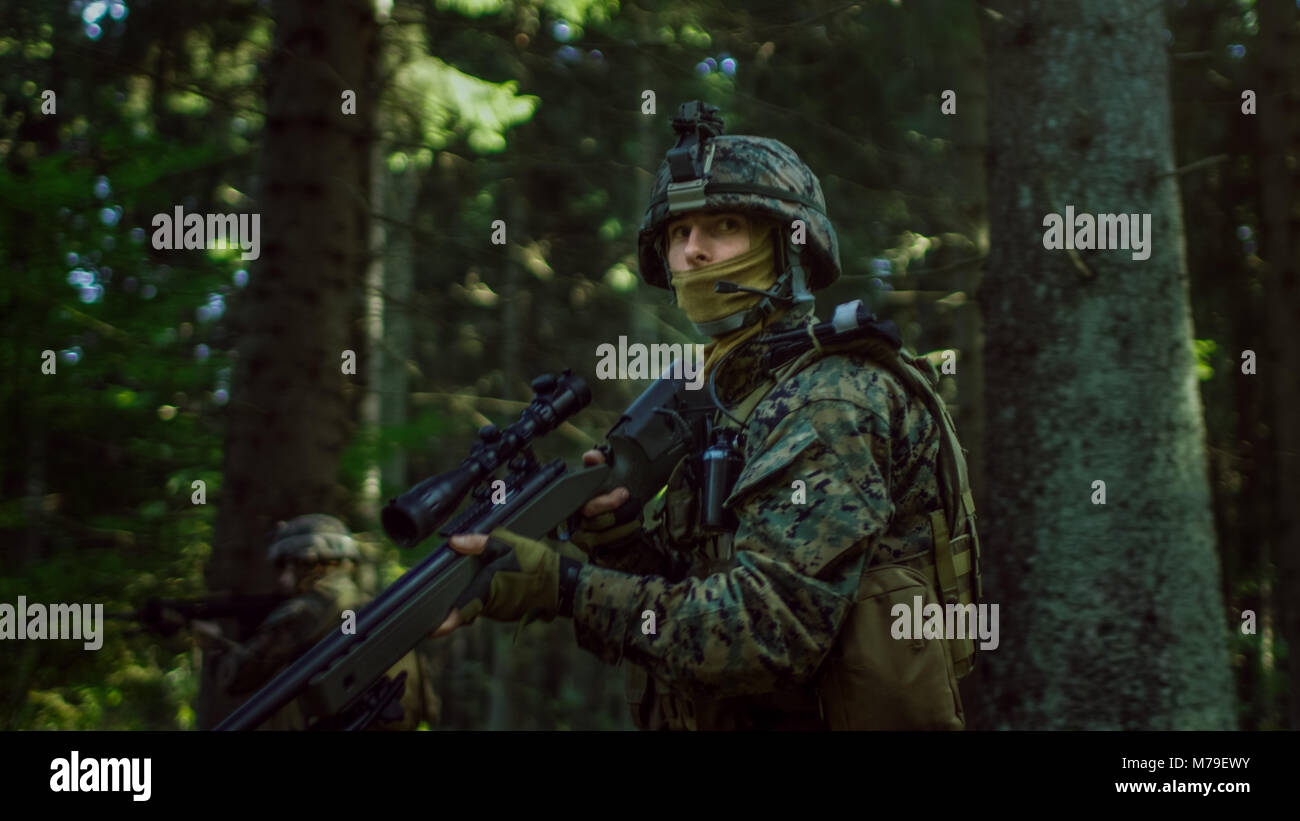 Voll Scharfschütze Soldat Tarnfarbe tragen Einheitliche angreifenden Feind, Gewehr im Anschlag ausgestattet. Militärische Operation in Aktion im Wald. Stockfoto