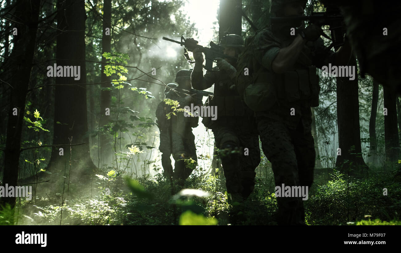 Gruppe von fünf voll ausgestatteten Soldaten in der Tarnung auf eine Aufklärung militärische Mission, Gewehre bereit zu schießen. Sie durch den Wald. Stockfoto