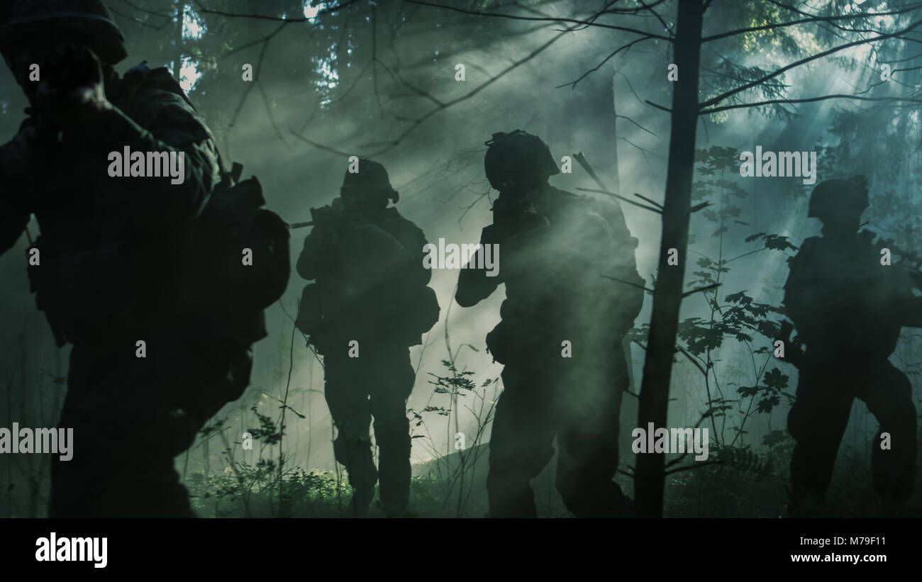 Gruppe von fünf voll ausgestatteten Soldaten in der Tarnung auf eine Aufklärung militärische Mission, Gewehre bereit zu schießen. Sie durch den Wald. Stockfoto