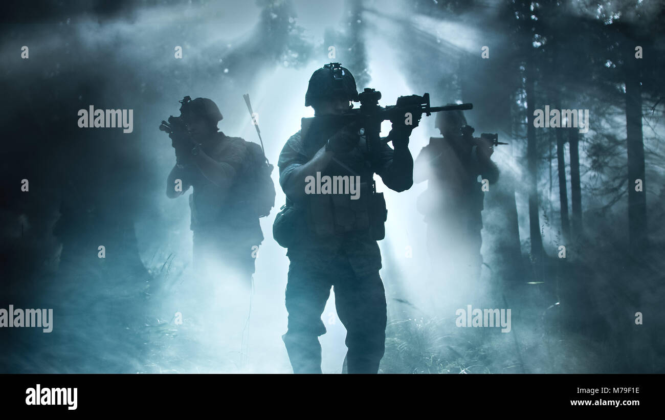 Silhouette der voll ausgestatteten Soldaten Bewegen durch Smokey Wald mit Gewehr bereit zu schießen. Aufklärung der militärischen Operation. Squad ist in Bewegung. Stockfoto