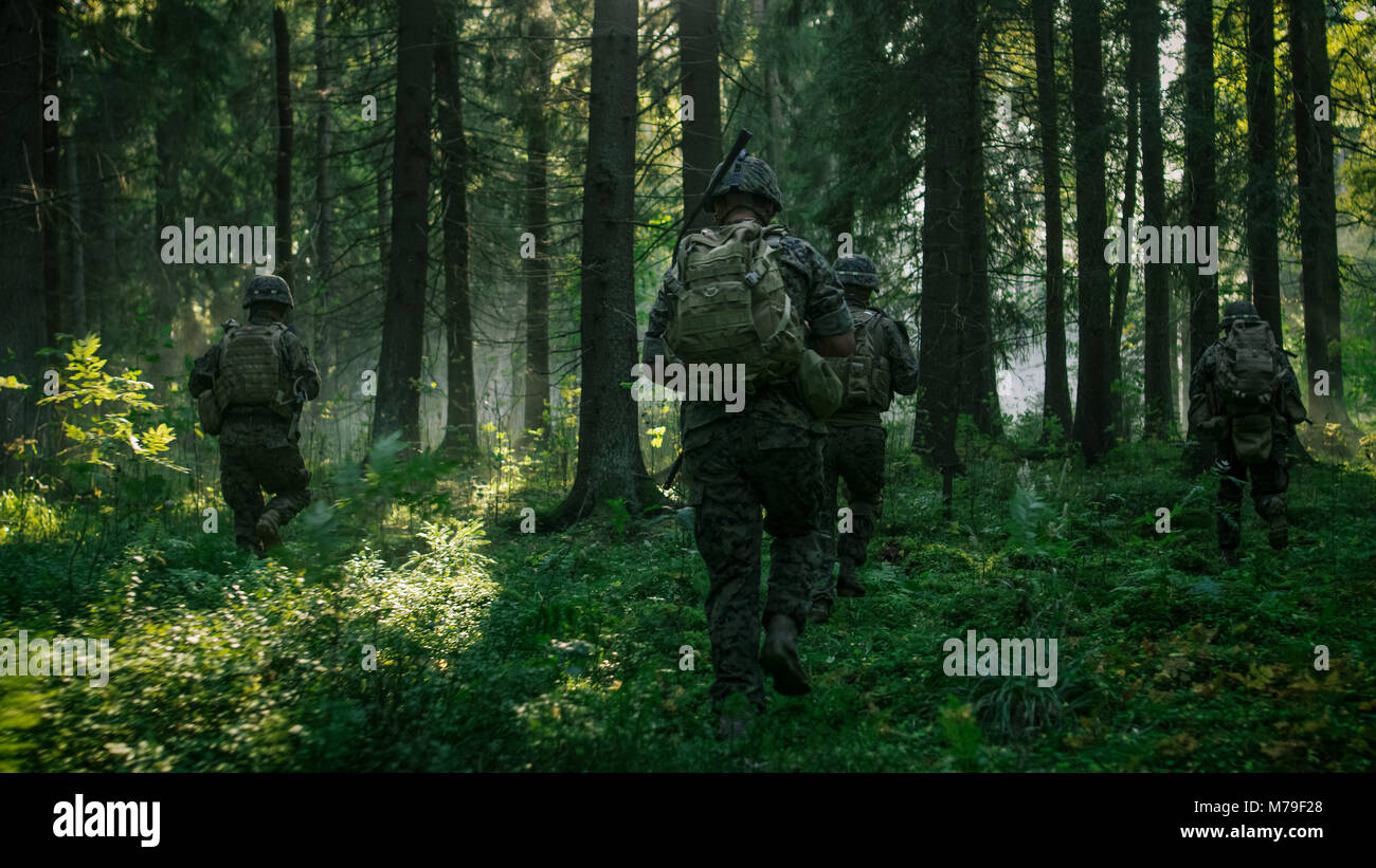 Voll ausgestattete Soldaten tragen Camouflage Einheitliche angreifenden Feind, Gewehre bereit zu schießen. Militärische Operation in Aktion, Gruppe durch den Wald zu laufen. Stockfoto