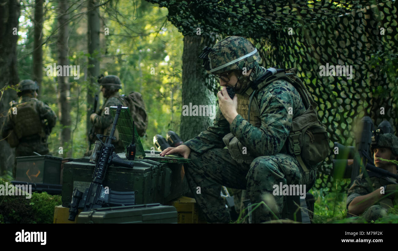 Militärische Inszenierung Base, Chief Army Engineer verwendet Walkie-Talkie-Radio und Armee Grade Laptop. Squads befindet sich getarnt Zelt auf Mission. Stockfoto