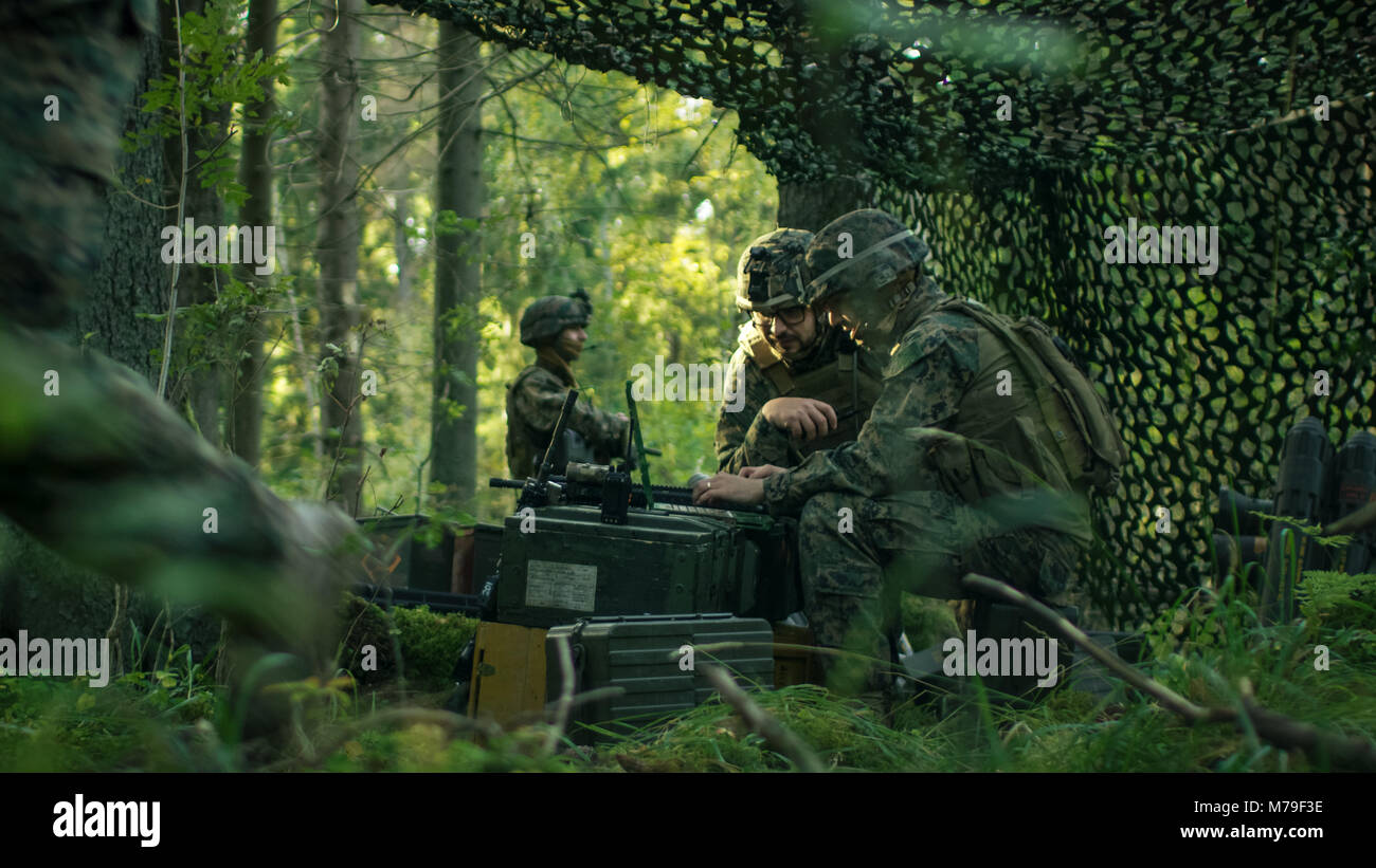 Militärische Inszenierung Base, Offizier gibt Aufträge zu Sichestellen, verwenden Sie Radio und Armee Grade Laptop. Sie sind in getarnt Zelt in einem Wald. Stockfoto
