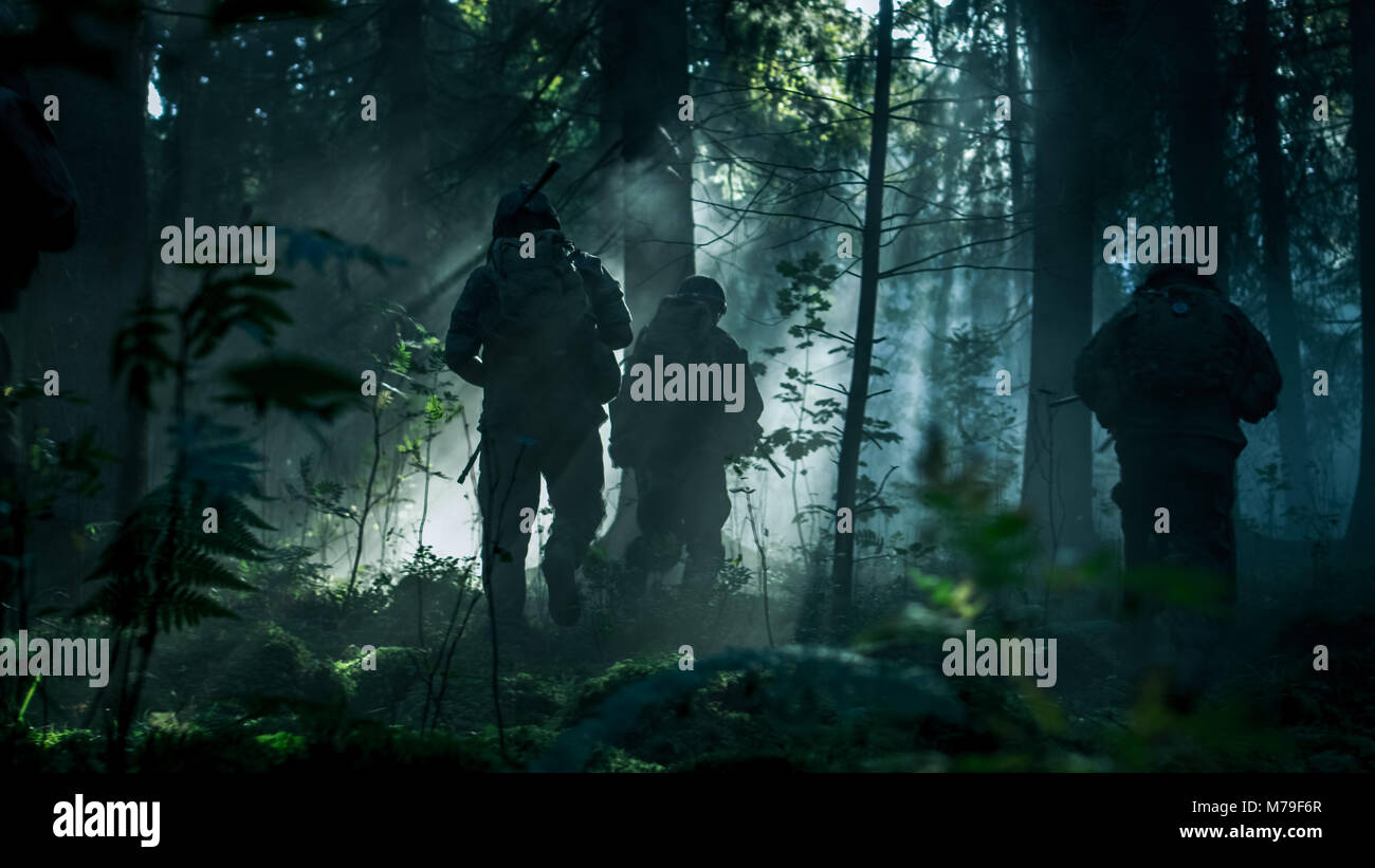 Gruppe von fünf voll ausgestatteten Soldaten in der Tarnung auf eine Aufklärung militärische Mission, Gewehre in Anschlag. Sie laufen durch den Wald Stockfoto