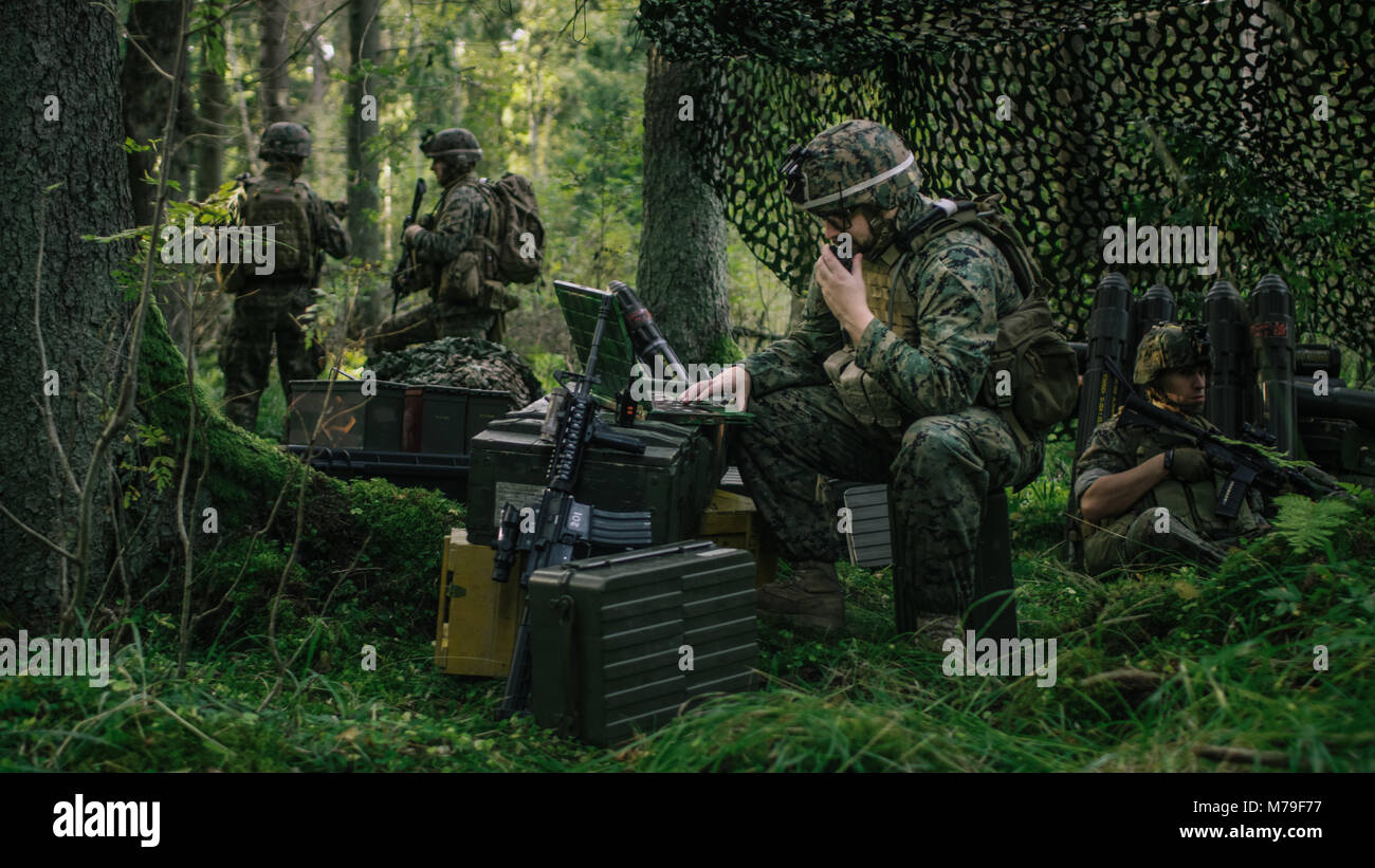Militärische Staging Area, Chief Engineer verwendet Radio und Armee Grade Laptop. Wald Betrieb/Mission im Gange. Stockfoto
