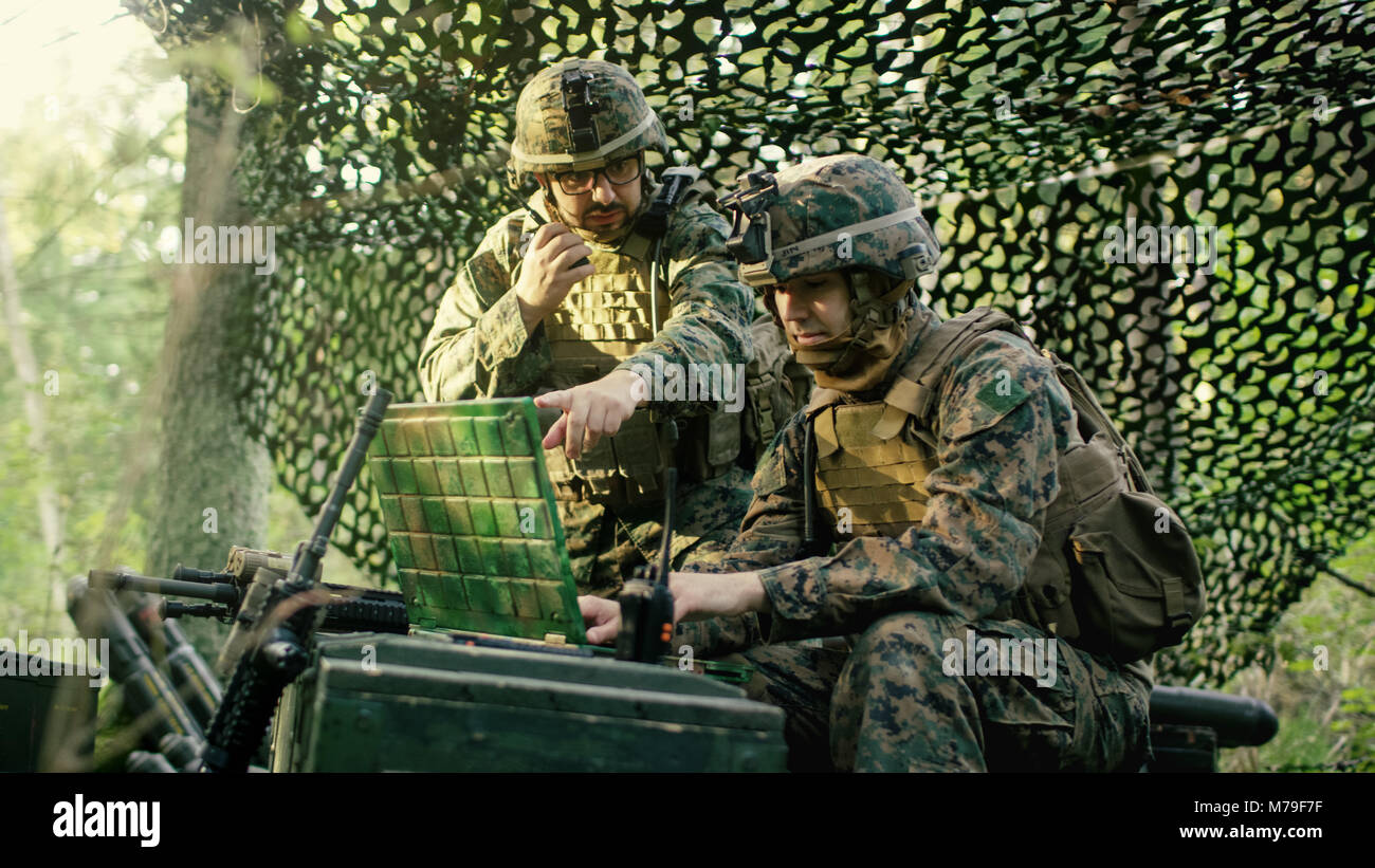 Militärische Inszenierung Base, Chief Engineer verwendet Radio und Armee Grade Laptop. Wald Betrieb/Mission im Gange. Stockfoto