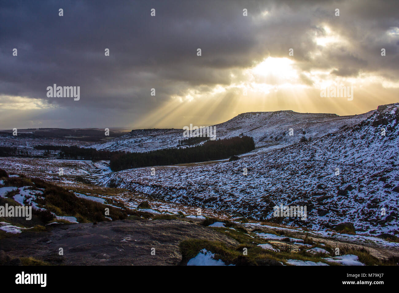 Sonnenstrahlen durch die Wolken an einem verschneiten Tag, Burbage, Peak District Stockfoto