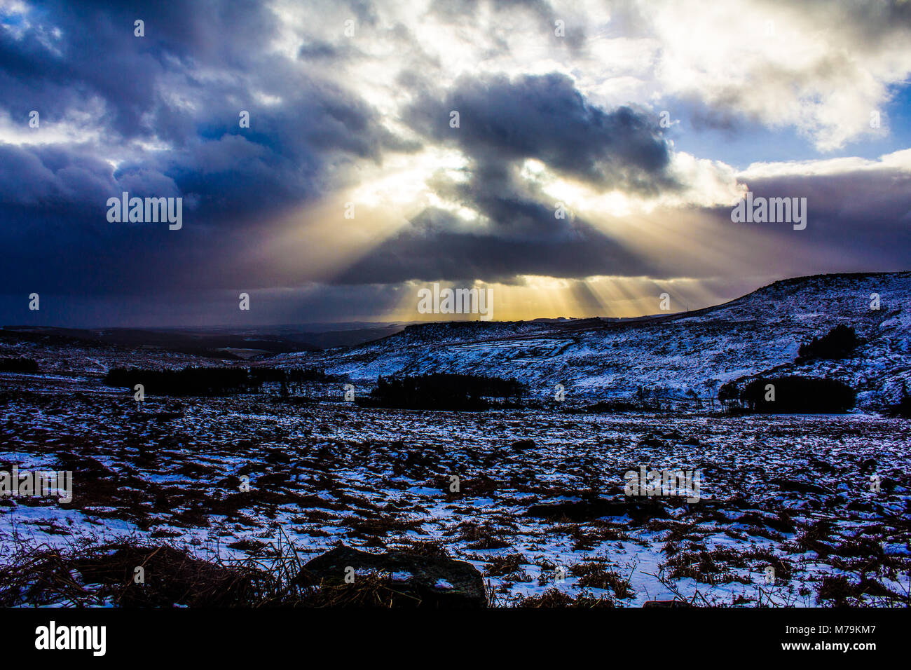 Sonnenstrahlen durch die Wolken an einem verschneiten Tag, Burbage, Peak District Stockfoto