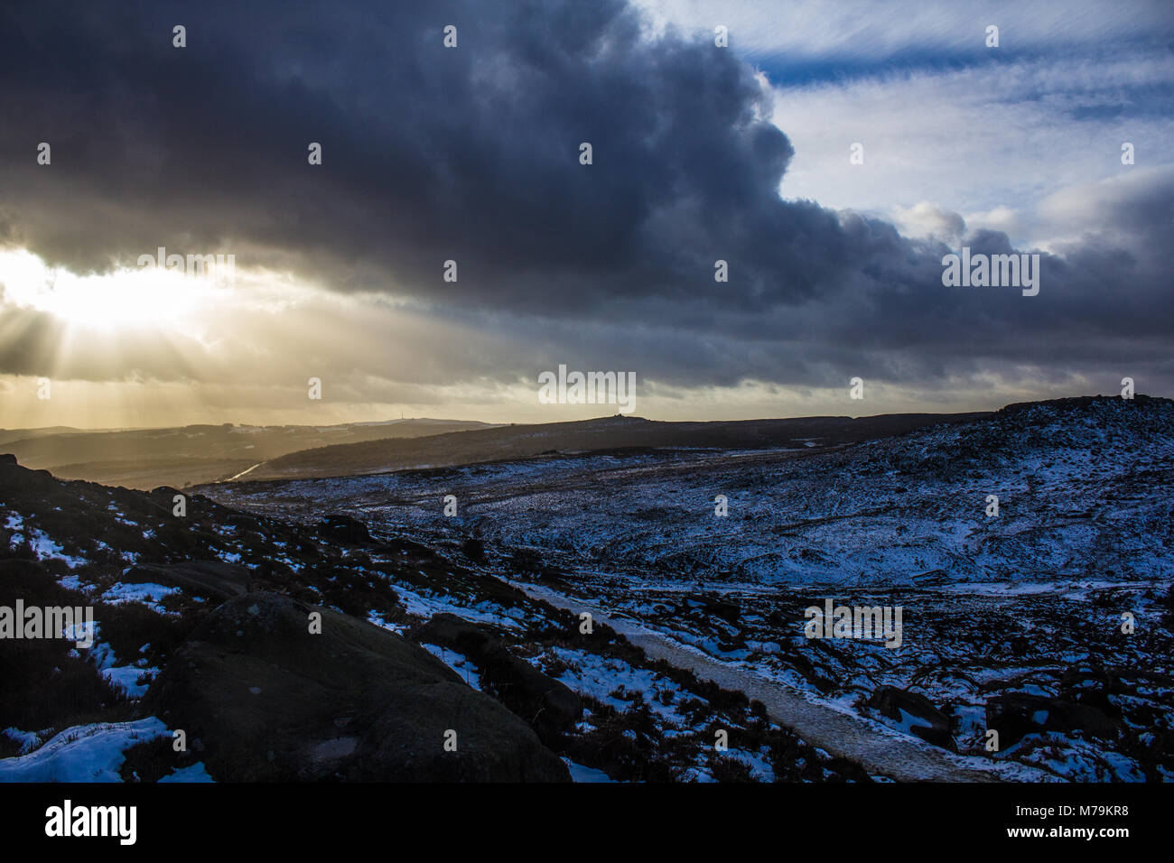 Sonnenstrahlen durch die Wolken an einem verschneiten Tag, Burbage, Peak District Stockfoto