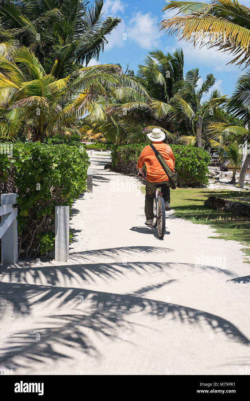 Ein Mann auf einen Sandweg in San Pedro, Belize auf der Insel Ambergris Radfahren. Stockfoto